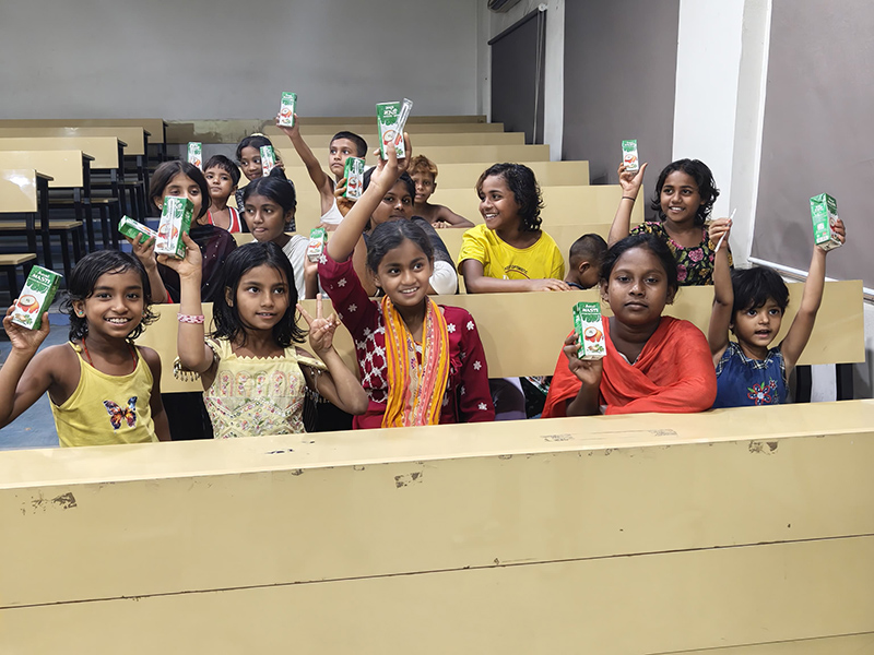 Children smiling as they receive buttermilk from the NSS volunteers on World Health Day.